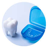 composed image containing a large tooth model and an open translucent blue dental case with a clear dental appliance in the case